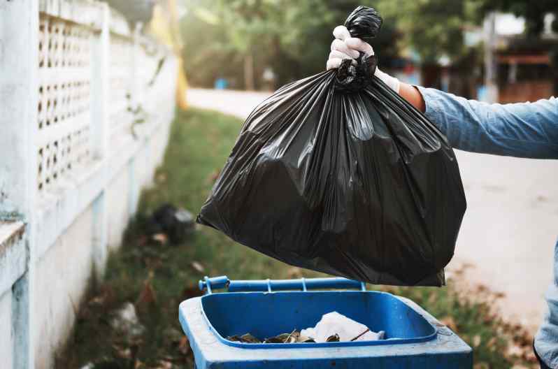 Person throwing away trash after a sewage backup in the basement