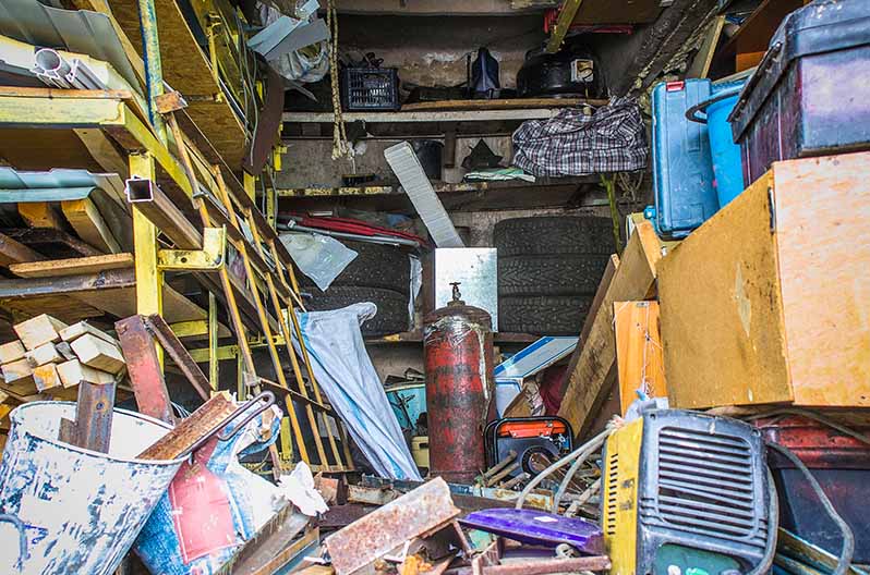 Messy clutter fills the inside of a garage of a stage three hoarder
