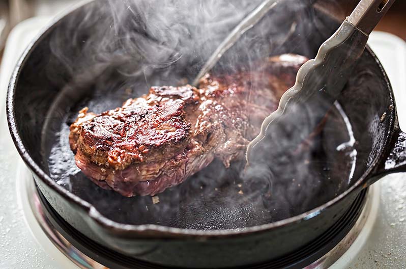A nearly invisible protein fire caused by searing a steak in a hot cast iron skillet